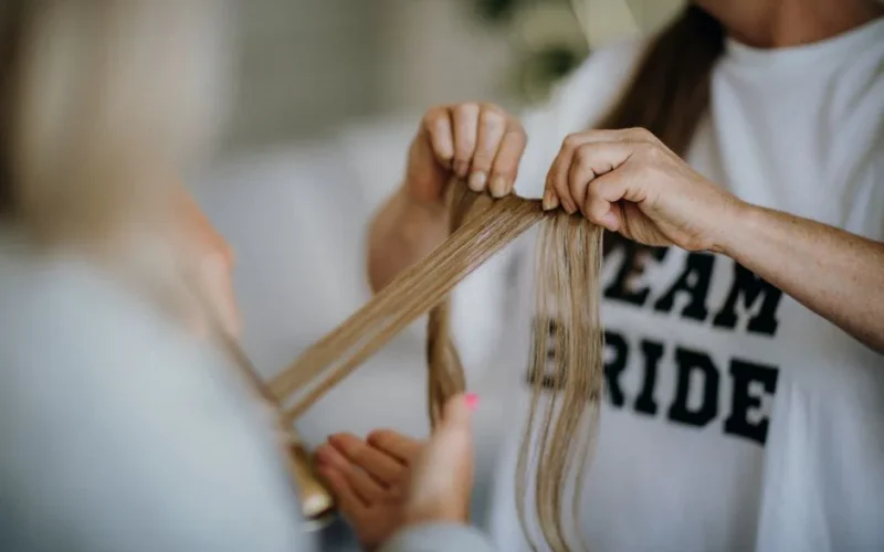 Bride's hair being styled, emphasizing a close-up of hands and long hair strands in preparation for a wedding.