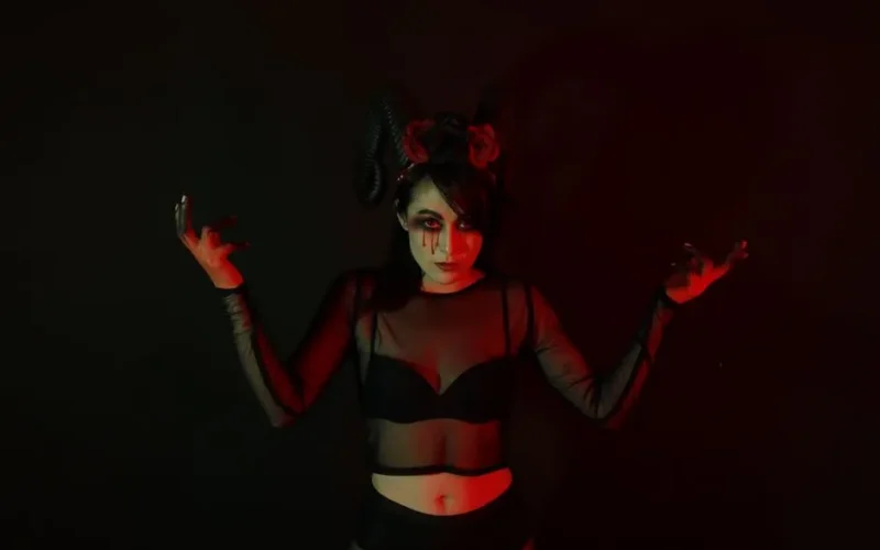 Creative portrait of a woman in dark costume with horns and red lighting, evoking a mystical mood.