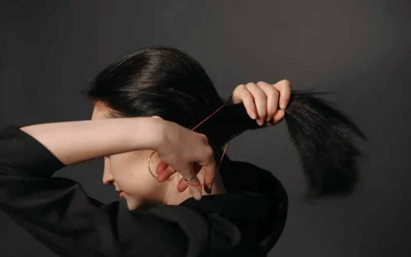 Close-up of a woman tying her hair with a rubber band. Focus on hands and hair.