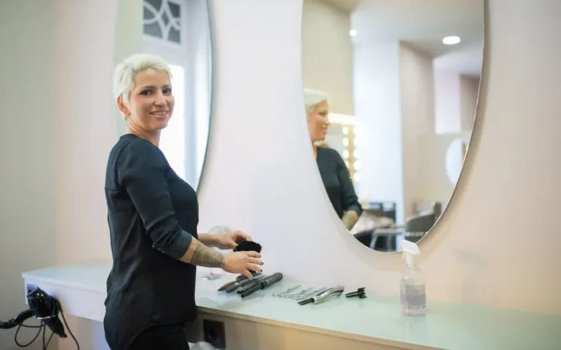 A hair stylist in a modern salon in Portugal with tools and a mirror.