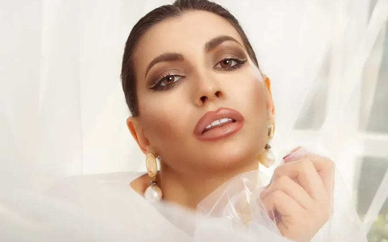 Stunning close-up portrait of an elegant woman with pearl earrings and flawless makeup.