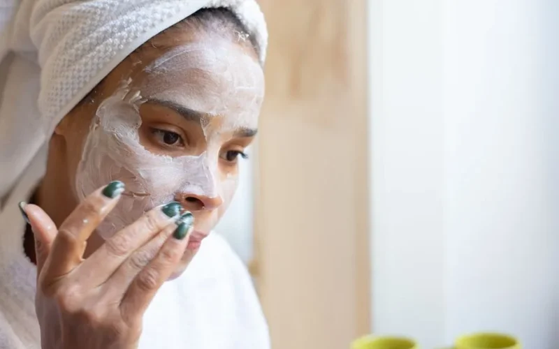 A woman applies moisturizing cream on her face during a home spa routine, enhancing her skincare regimen.