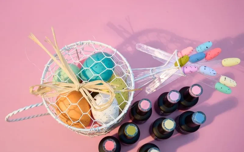 Vibrant Easter egg arrangement with colorful nail polish on a pink backdrop.
