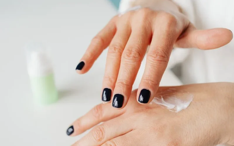 Close-up of a woman applying hand cream for moisturizing.