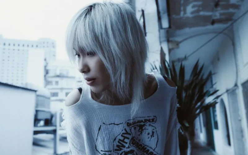 Stylish portrait of a person with platinum hair in an urban setting, captured in cool tones.