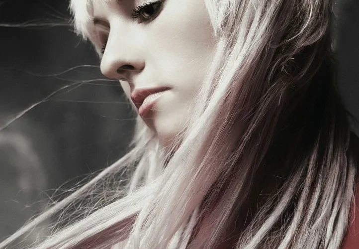 Artistic portrait of a woman with flowing platinum hair and soft lighting.