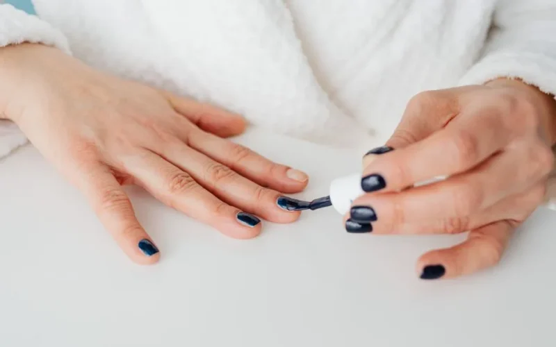 Close-up of a woman applying dark nail polish for a stylish manicure.