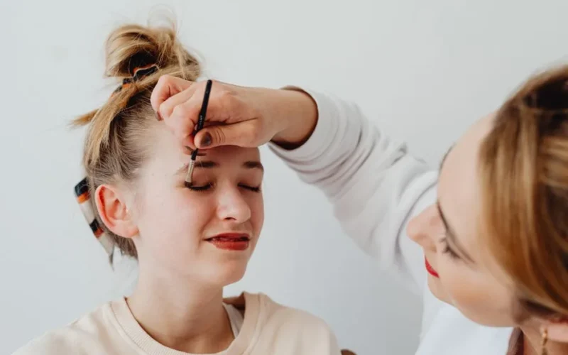 Two women engaged in a makeup application session with focus on eyeshadow.
