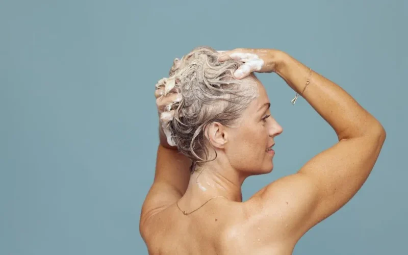 Woman shampooing her hair, showing a personal care routine with soap suds.