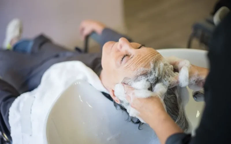 Woman enjoying a relaxing hair wash with shampoo and massage in a modern hair salon.