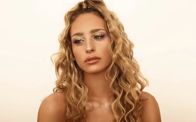 Stylish portrait featuring a woman with blonde curly hair and glamorous makeup