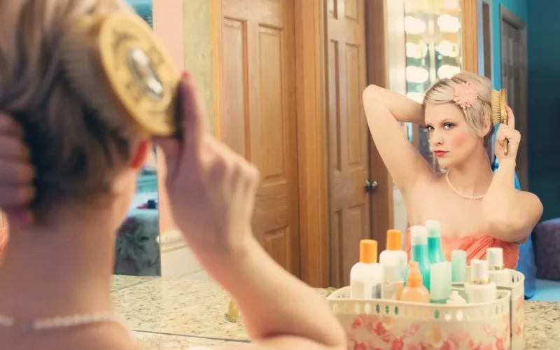 A woman elegantly brushing her hair in front of a mirror, capturing a vintage style.
