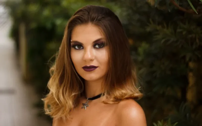 Elegant portrait of a woman with smokey makeup, bold lipstick, and an alluring stare.