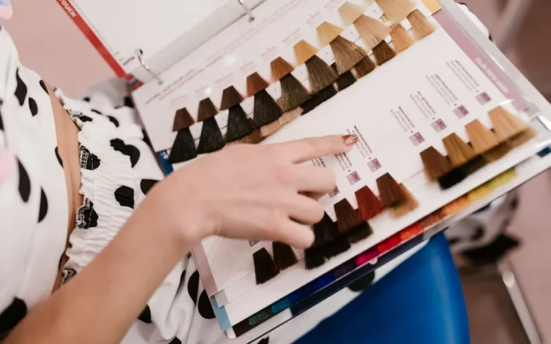 Woman selecting hair color samples in a salon, showcasing shades of brown and blonde.
