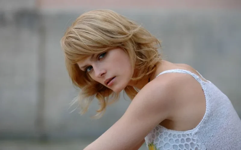 Portrait of a stylish woman with blond hair wearing a white crochet top, outdoors.