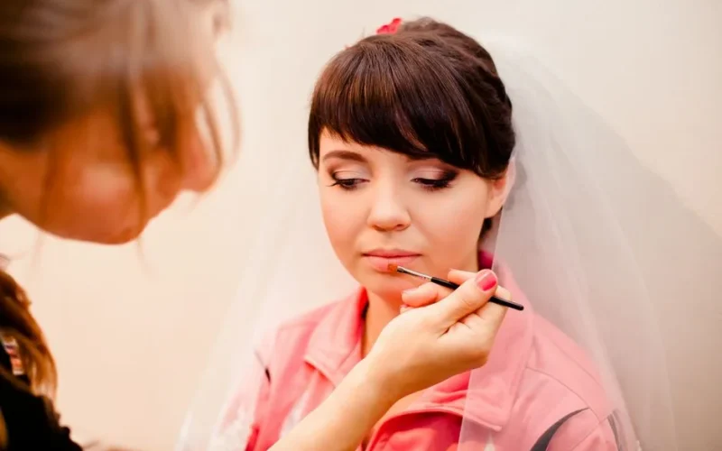 A bride getting her makeup done before the wedding ceremony.