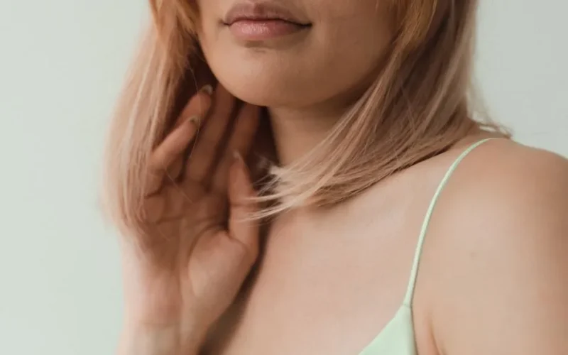 Close-up portrait of a woman with blonde hair and spaghetti strap top, highlighting soft, natural beauty.