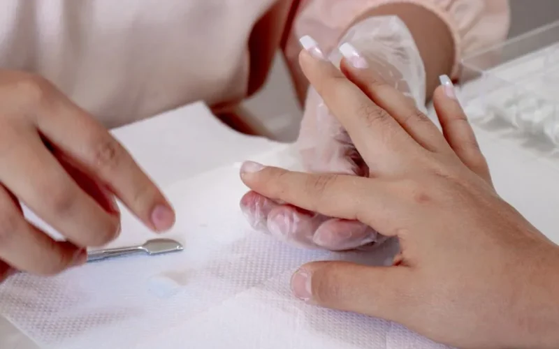 Detailed view of a manicure session with hands and nail tools on a table.