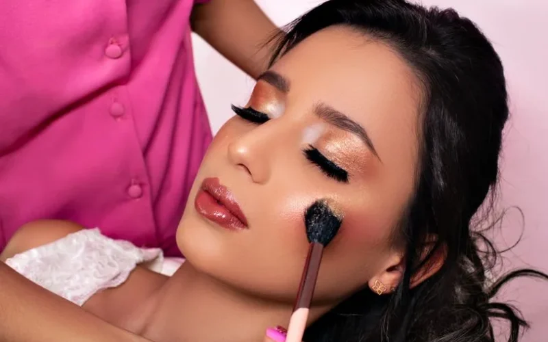 Close-up of a beautician applying makeup on a woman's face for a glamorous evening look.