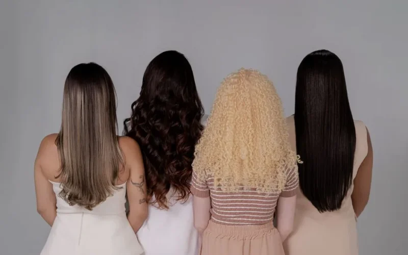 Four women showing diverse hairstyles from behind, emphasizing hair texture and color.