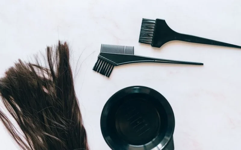 Top view of hair coloring tools and hair strands on a white background.