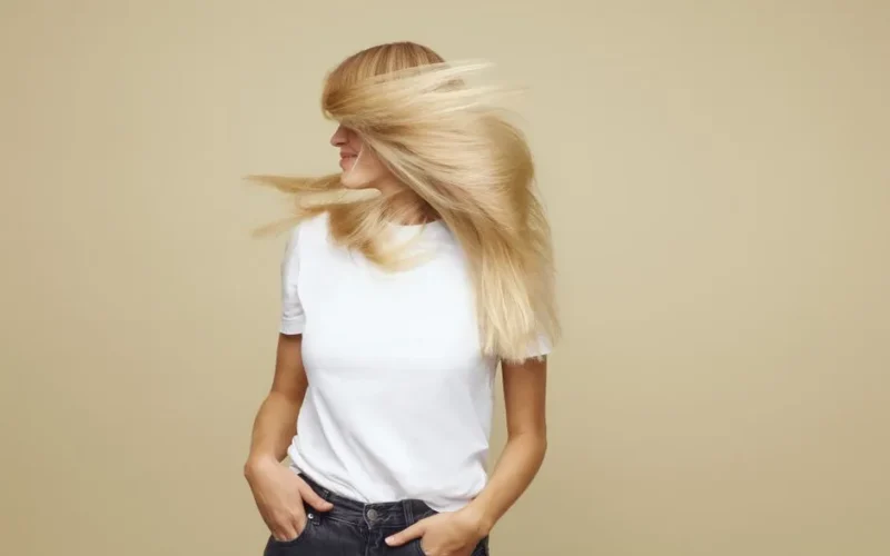 Stylish blonde woman in motion, showcasing hair care and fashion in Copenhagen.