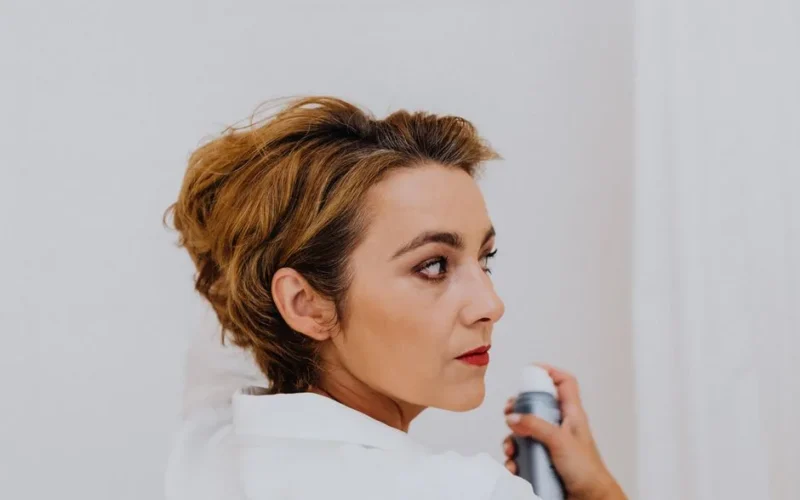 Side view of a mature woman applying hairspray with elegance. Perfect for beauty and style themes.