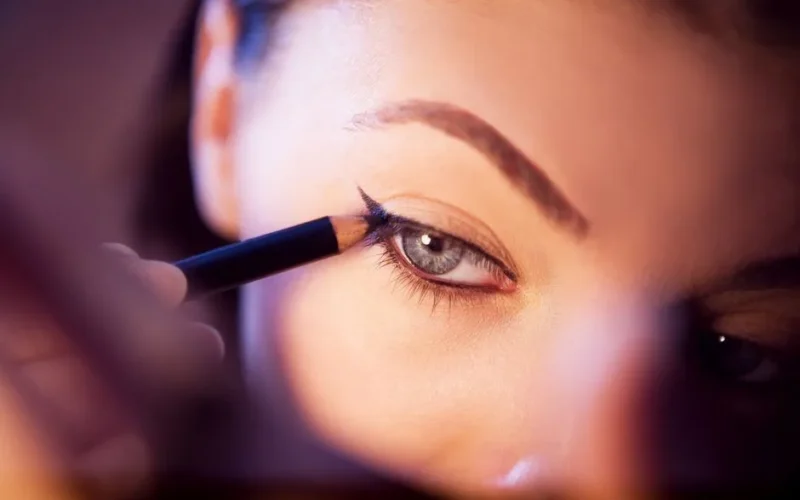 A close-up shot of a woman applying eyeliner with precision.