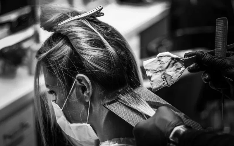 Monochrome image of a woman getting her hair colored in a salon.
