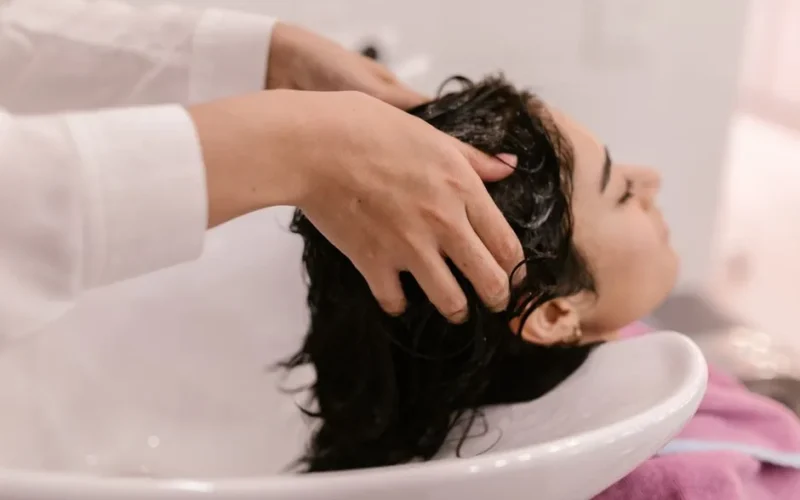 A woman enjoys a relaxing hair wash at a salon. Captured in a cozy indoor setting.