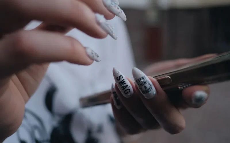 Close-up image showcasing detailed nail art on hands holding a smartphone. Modern and trendy design.